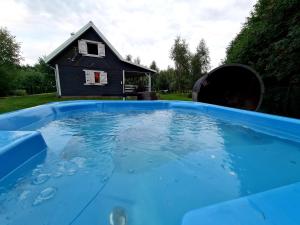 a pool of water with a house in the background at Szary Domek 1 jacuzzi kominek sauna klimatyzacja jezioro in Piotrków Kujawski