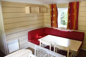 ein kleines Zimmer mit einem roten Sofa und einem Tisch in der Unterkunft Entre sable et feuillus in Camiers