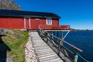 a red building with a wooden bridge next to the water at Å-Hamna Rorbuer in Å