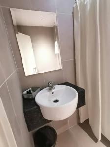 a bathroom with a white sink and a mirror at Serapi Verdure Hotel in Kuching