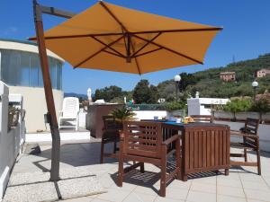 um guarda-sol num pátio com uma mesa e cadeiras em La terrazza tra il Mare e gli Ulivi by Holiday World em Lavagna