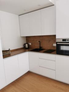 uma cozinha branca com uma pia e um micro-ondas em Jorė em Juodkrantė mais 43 fotografias