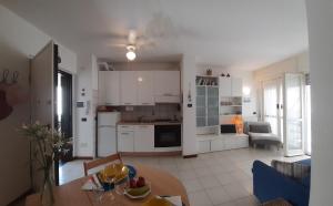 uma cozinha e sala de estar com armários brancos e uma mesa em La terrazza tra il Mare e gli Ulivi by Holiday World em Lavagna