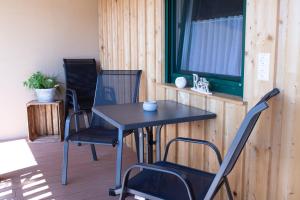 a table and chairs on a porch with a window at Rebenhof Schwalm in Herrnbaumgarten