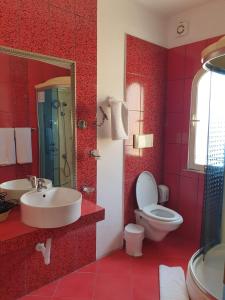 een rode badkamer met een wastafel en een toilet bij Theranda Boutique Hotel in Tirana