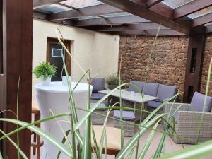 eine Terrasse mit Stühlen, Tischen und einer Steinmauer in der Unterkunft Restaurant & Hotel Exquisite in Bobenheim am Berg