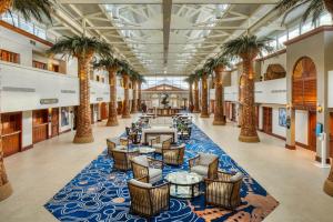 a lobby with palm trees and tables and chairs at TradeWinds Island Grand in St Pete Beach