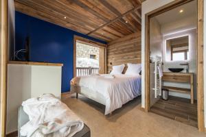 - une chambre avec un grand lit et des murs bleus dans l'établissement CAPRICORNE - Chalet sur les pistes avec sauna et home cinema, à La Toussuire