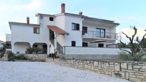 una grande casa bianca con un muro di pietra di Apartments Brcic a Tar