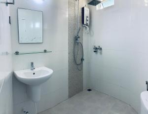 La salle de bains blanche est pourvue d'un lavabo et d'une douche. dans l'établissement ilaa Beach Maldives, à Gulhi