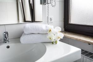 a bathroom sink with towels and flowers on it at Hotel Avenue Altenfurt in Nuremberg