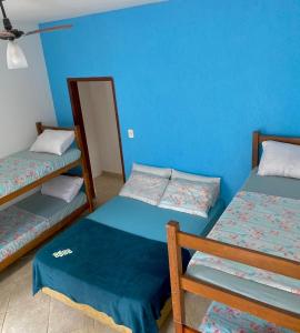 a room with two bunk beds and a blue wall at Pousada Cauna in Caraguatatuba