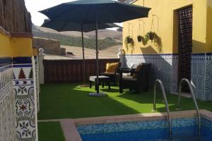 un patio con sombrilla, sillas y piscina en Casa rural Los Alcaidejos con piscina, en Málaga