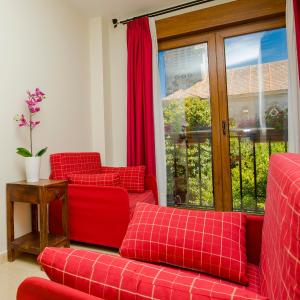 salon z 2 czerwonymi kanapami i oknem w obiekcie Hotel Arce w mieście Baiona