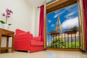 Habitación con silla roja y ventana con vistas. en Hotel Arce, en Baiona