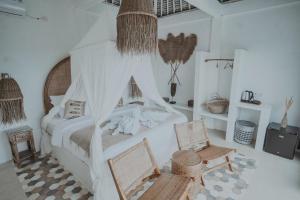 een slaapkamer met een hemelbed en 2 stoelen bij Woywoy Escape Bresela Adults Only in Tegalalang