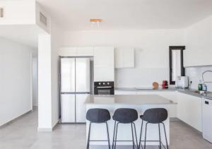 a kitchen with two bar stools and a white counter at O&O Group- Magical 4BR APT With Panoramic Sea View in Bat Yam