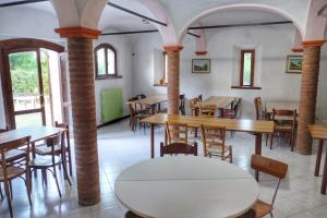 a dining room with tables and chairs and windows at Acatú in Monzuno