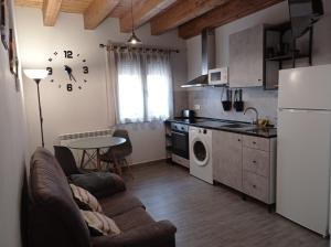 a kitchen with a couch and a table and a refrigerator at Apartamentos CASA RURAL EL VENTANICO in Olocau del Rey
