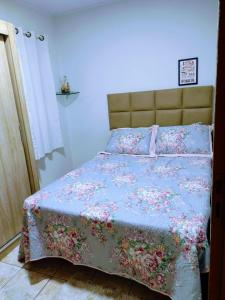 a bedroom with a bed with a floral bedspread at Casa aconchegante ao lado da Igreja Matriz- Bananeiras-PB in Bananeiras