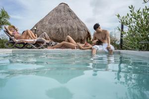 a group of people laying around a swimming pool at Sunset House in Tulum