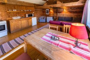 a wooden cabin with a wooden table and a kitchen at Klingenberg Rorbuer in Sørvågen