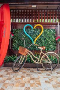 un vélo avec un panier en forme de cœur garé à côté d'une clôture dans l'établissement Pousada Oásis, à Peruíbe