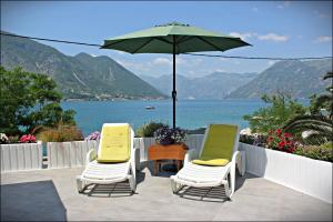 dwa krzesła i stół z parasolem na patio w obiekcie Accommodation Tomcuk w Kotorze