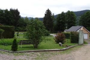 a park with a bench and a tree and a house at Profiter du calme de la montagne vosgienne in Saulxures-sur-Moselotte