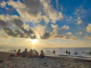 een groep mensen die op het strand zitten en naar de zonsondergang kijken bij Case Vacanze Mare Nostrum - Villas in front of the Beach with Pool in Campofelice di Roccella