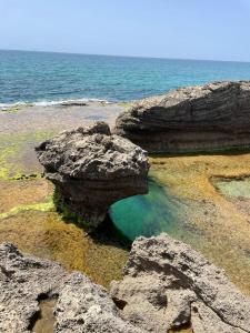 een grote rots in het water op het strand bij Zohara boutiqe suite in Caesarea