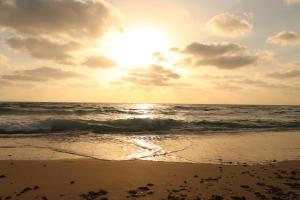 a beach with the sun setting over the ocean at Zohara boutiqe suite in Caesarea