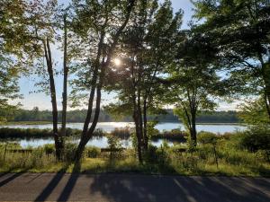 a view of a lake with the sun shining through trees at Pocono mountain hotel and spa in Gouldsboro