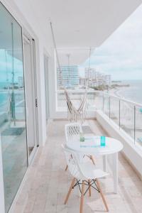 un balcón con una mesa y sillas blancas y el océano en Deluxe Spectacular Sunset en Santa Marta