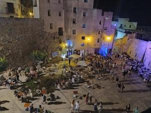 un gruppo di persone seduti fuori da un edificio di notte di Casas del Castillo Peñíscola-Intramuros Suites a Peñíscola