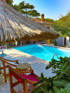 uma grande piscina com um guarda-sol de palha e uma mesa e cadeiras em Attalos Suites Hotel em Bergama