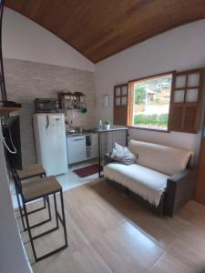 a kitchen with a couch and a refrigerator in a room at Recanto da Paz Ibitipoca com Hidromassagem in Conceição da Ibitipoca