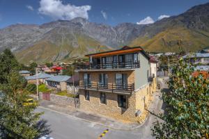 a building on a street with mountains in the background at Hotel INSIDE Kazbegi in Stepantsminda