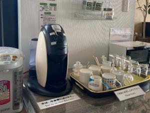 HOSTEL HIROSAKI - Vacation STAY 66581v في هيروساكي: آلة صنع القهوة على منضدة مع صينية من الأكواب