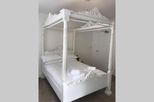 Cama blanca con dosel y almohadas blancas en Beautiful 2 bed flat in the heart of Lynton Devon, en Lynton