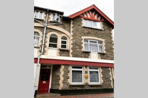 un edificio de ladrillo con ventanas y puerta roja en Beautiful 2 bed flat in the heart of Lynton Devon, en Lynton
