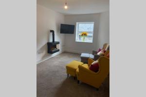 a living room with a yellow chair and a couch at Beautiful 2 bed flat in the heart of Lynton Devon in Lynton