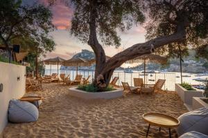 a beach area with chairs, tables, and umbrellas at Akrotiri Beach Resort Hotel in Paleokastritsa