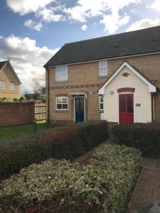 a brick house with a red door and a yard at Grant Close in Wickford