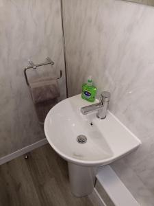 a white bathroom sink with a green container on it at Grant Close in Wickford