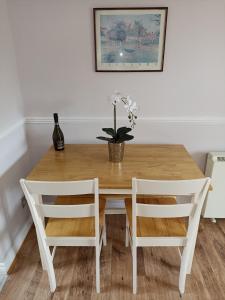 a wooden table with two chairs and a vase with flowers at Grant Close in Wickford