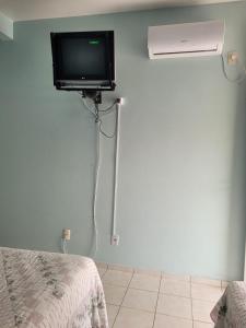 um quarto com uma televisão, uma ventoinha e uma cama em Pousada na Lagoa da Conceição Barcelos em Florianópolis