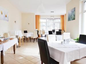 una sala da pranzo con tavoli e sedie bianchi di Gartenhotel LandArt a Bad Soden-Salmünster