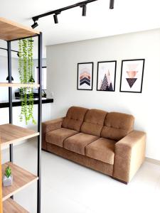 uma sala de estar com um sofá castanho em One 360 - Design Industrial - Ap para casais e família - 2 quartos com ar em Capitólio