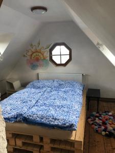 ein Schlafzimmer mit einem Bett mit blauer Bettdecke und einem Fenster in der Unterkunft Vila pod Ještědem in Liberec